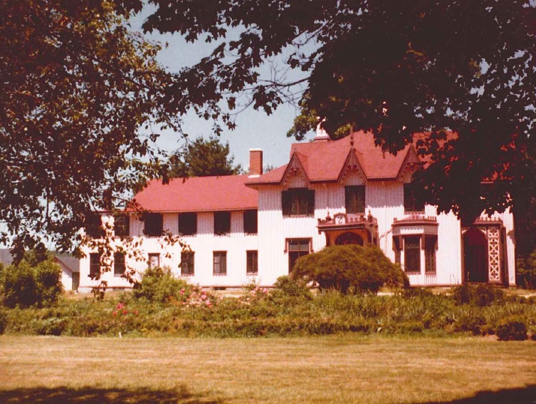 Lawn and overgrown garden in foreground, and Roseland Cottage behind garden.